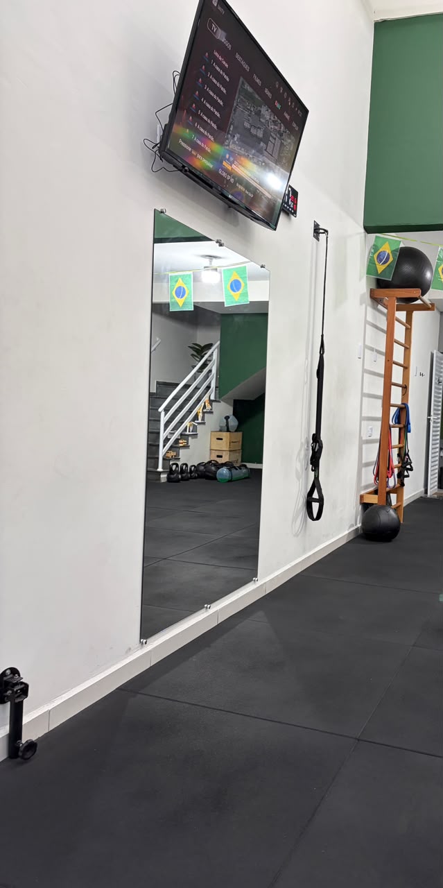 Espaço de treino com espelho e TRX